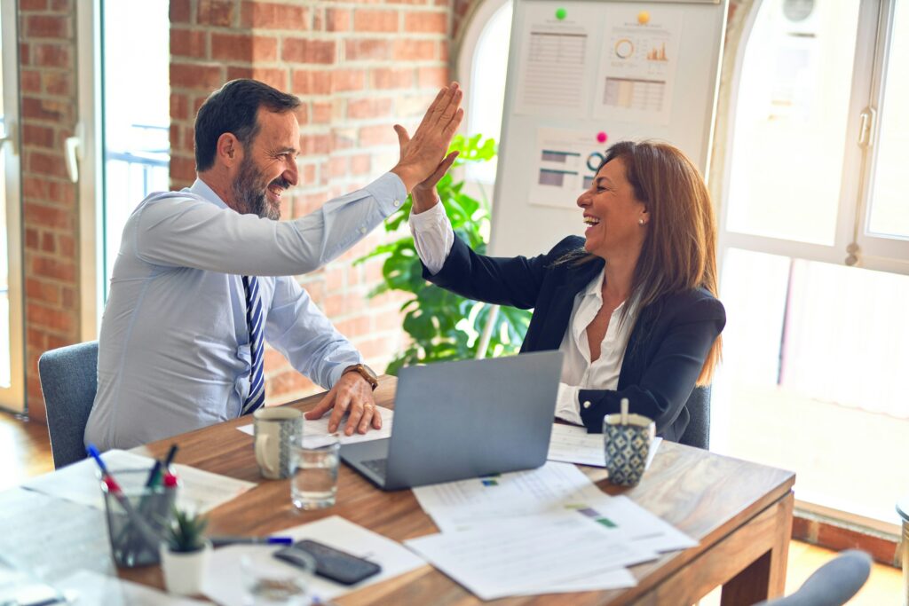 Two business people high-fiving in an office